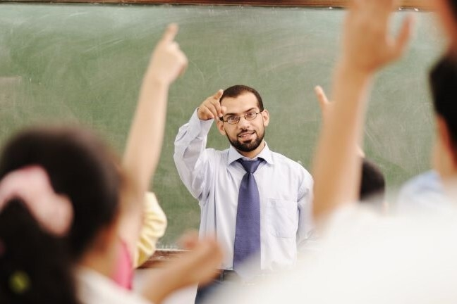 Male teacher with students hands raised