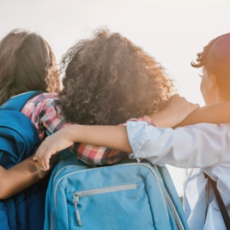 Three students with backpacks facing the sun